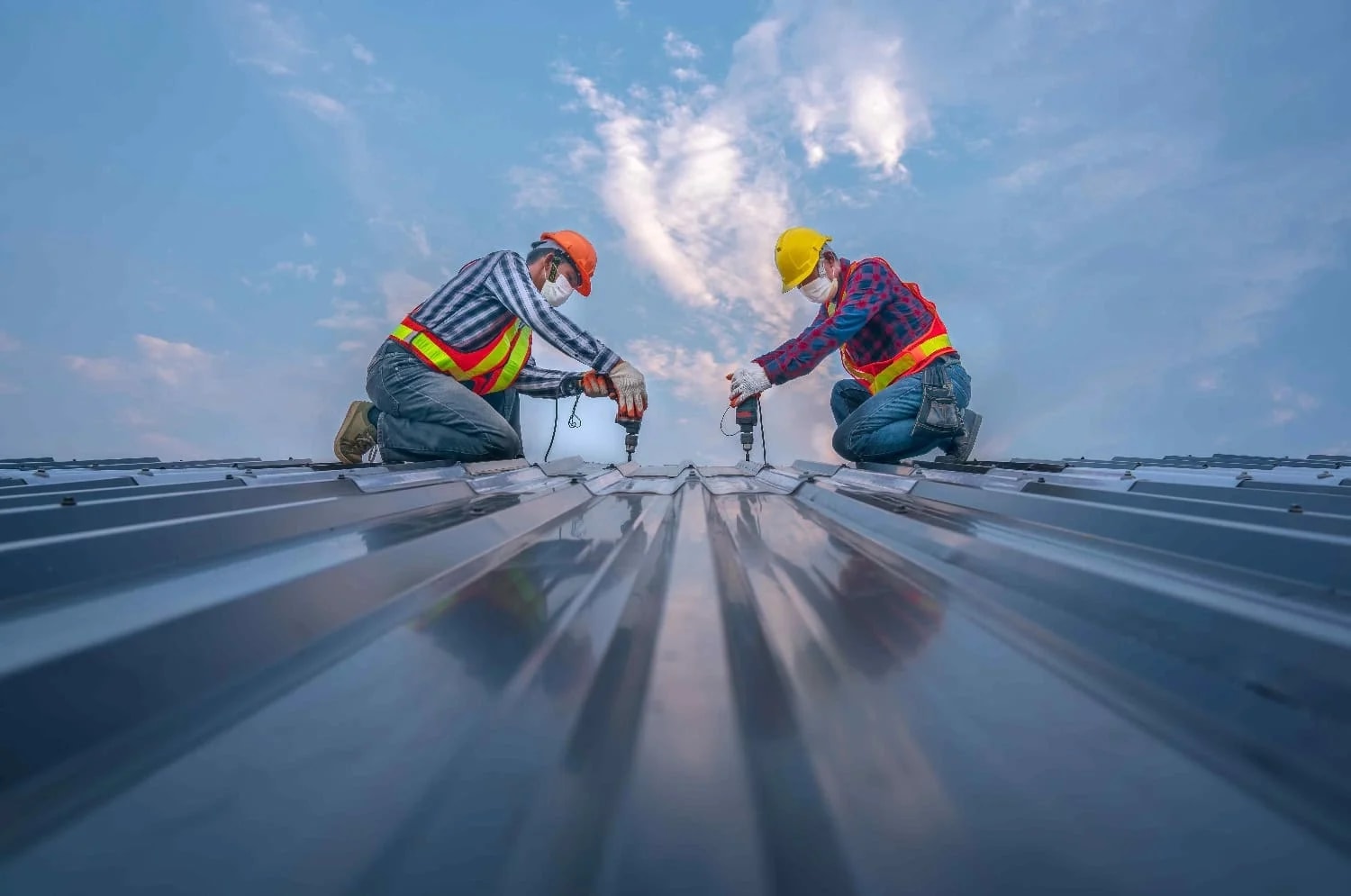 Roofers inspecting a large metal roof for commercial roof maintenance