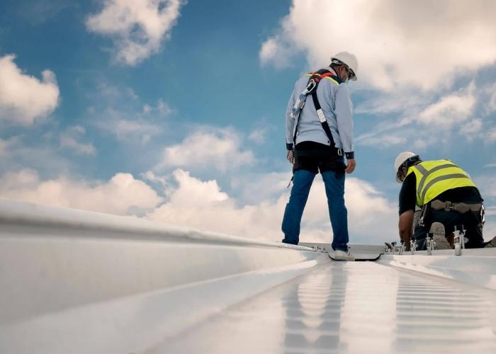 Roofers working on a low-slope commercial metal roof