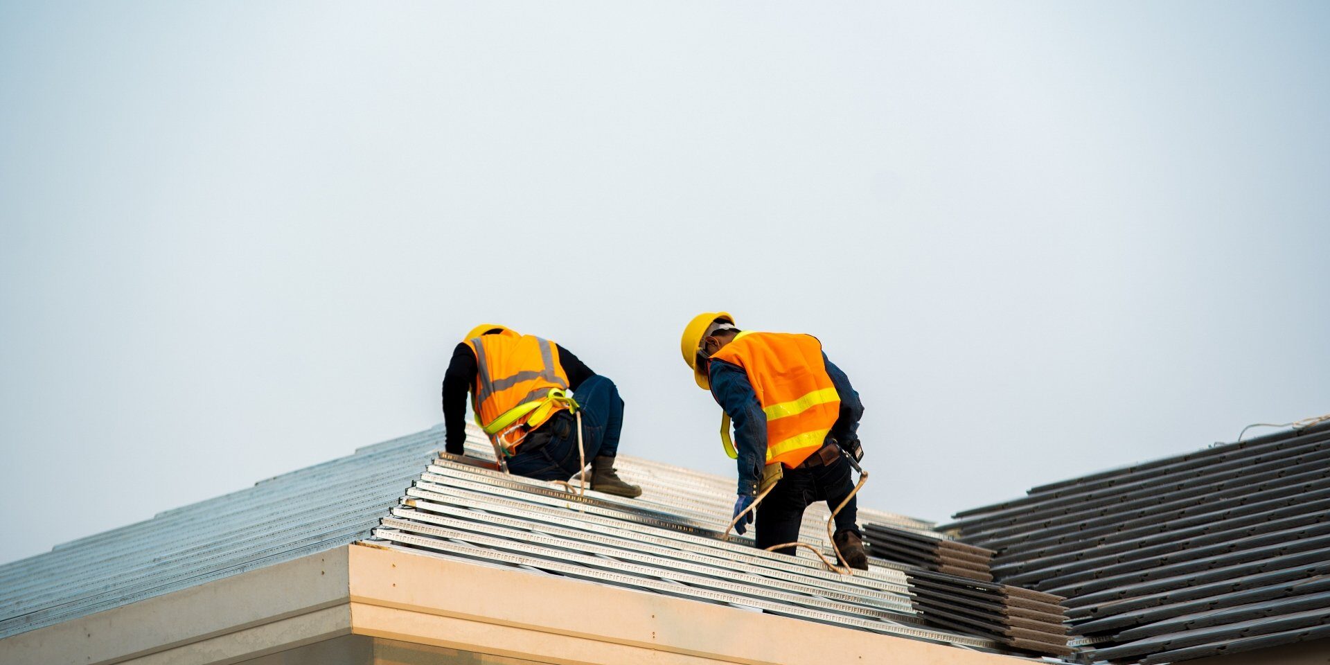 Roofers inspecting a roof with exposed sheeting and tiles