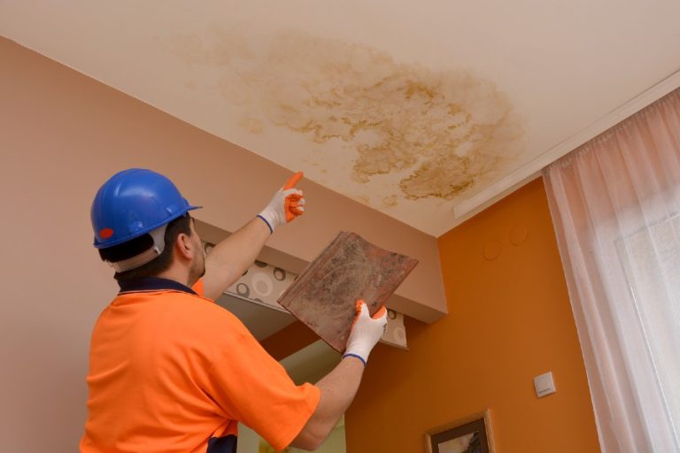 Roofer pointing to ceiling water damage from a roof leak
