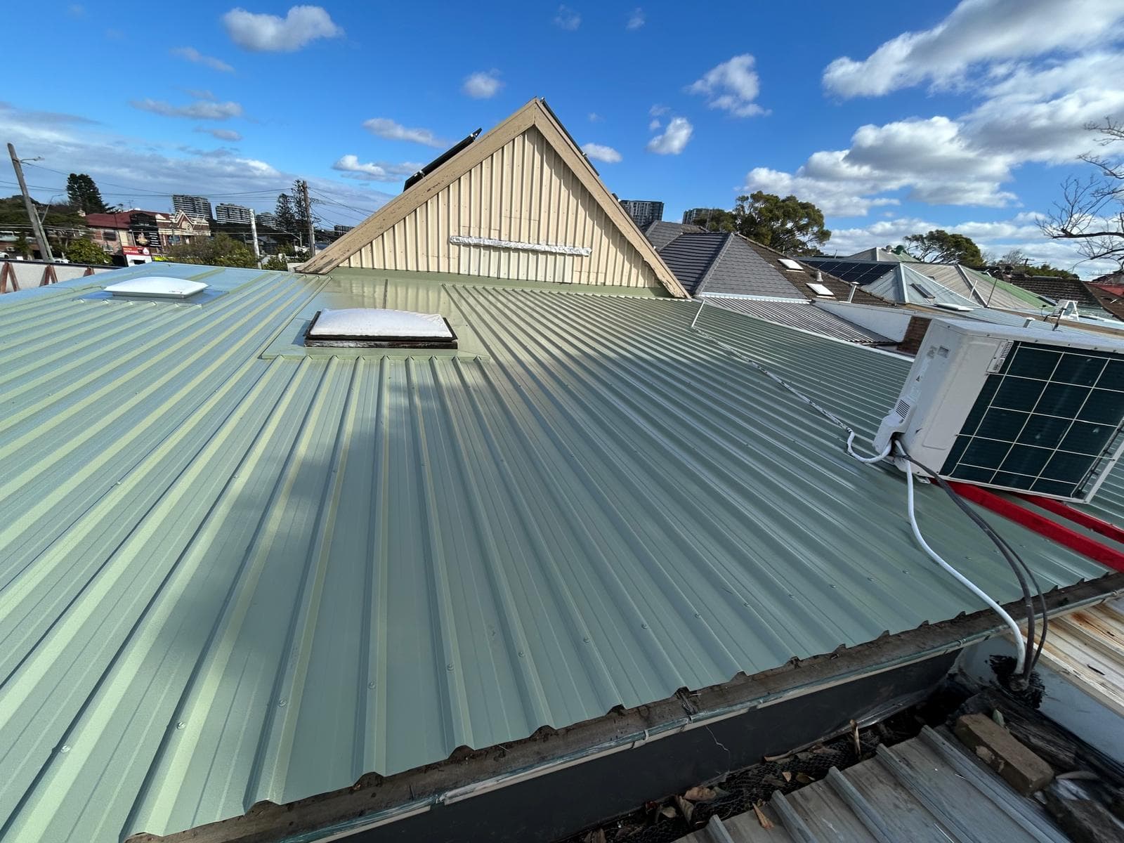 Pale green metal roof with a skylight on a character home