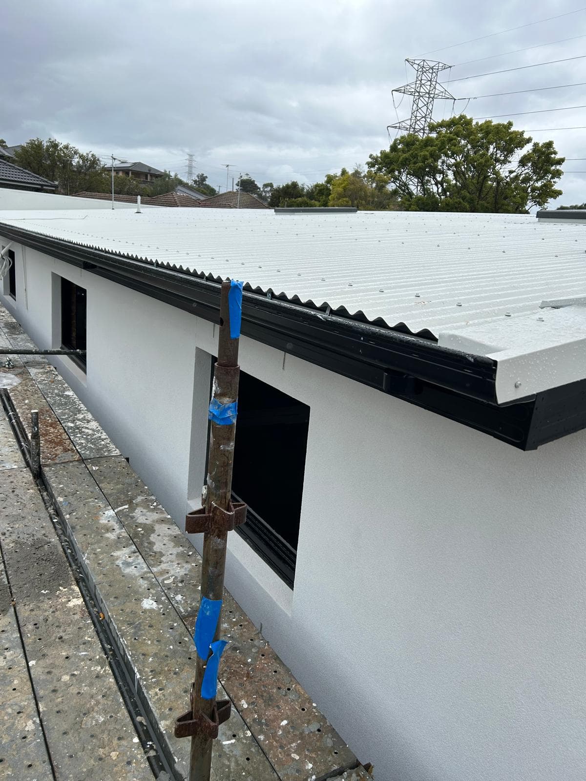 Commercial metal roof edge beside a larger building wall