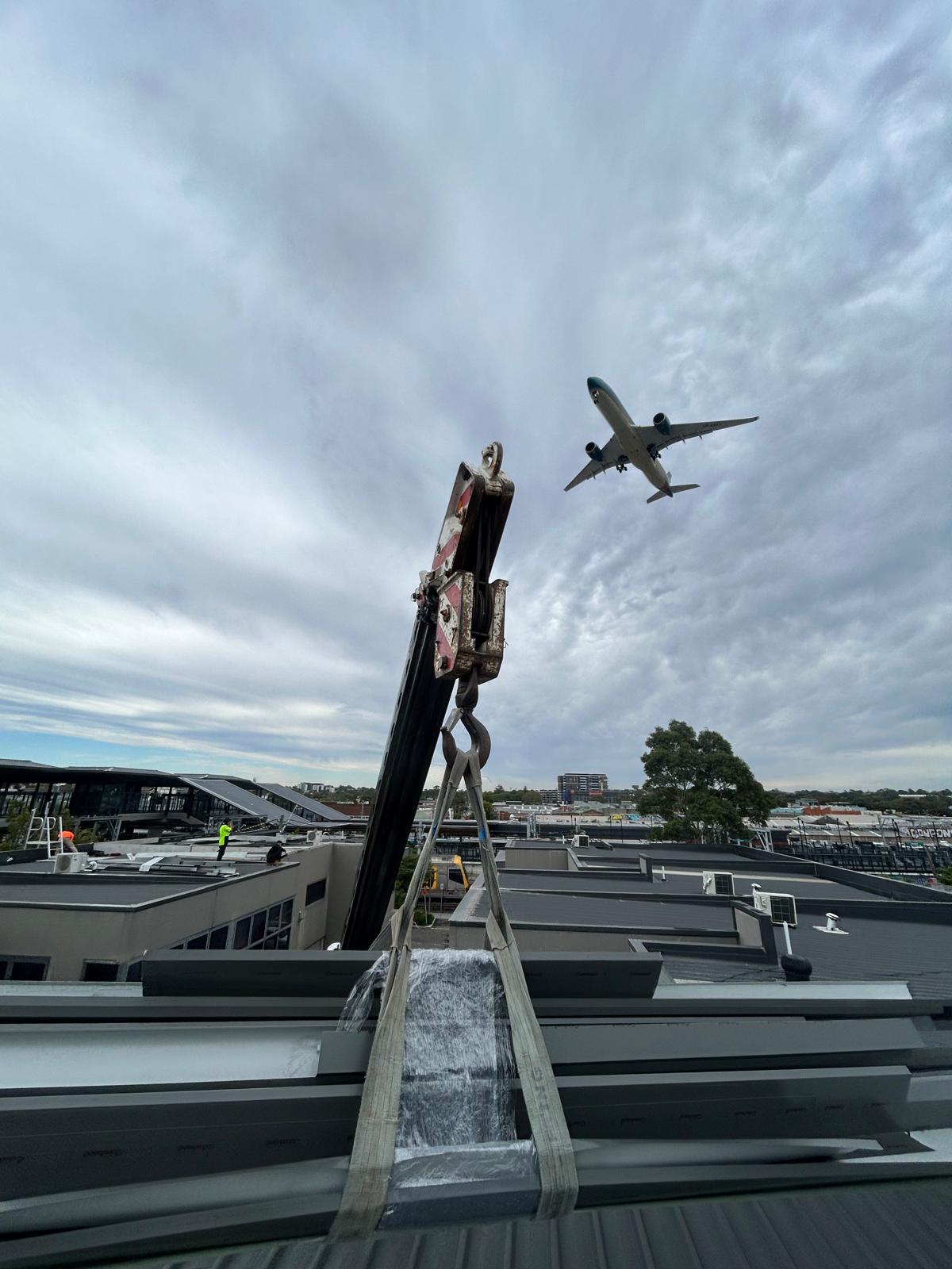 Industrial metal roof access view with skylights and aircraft overhead