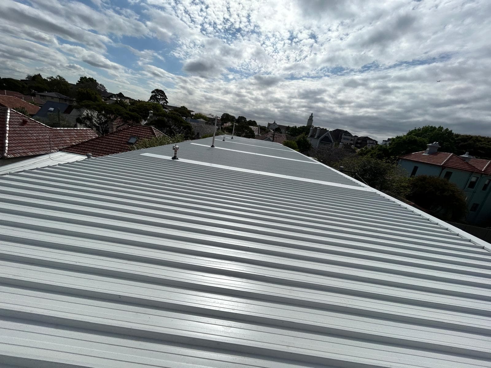 Wide view of light metal roof sheeting across a residential roof