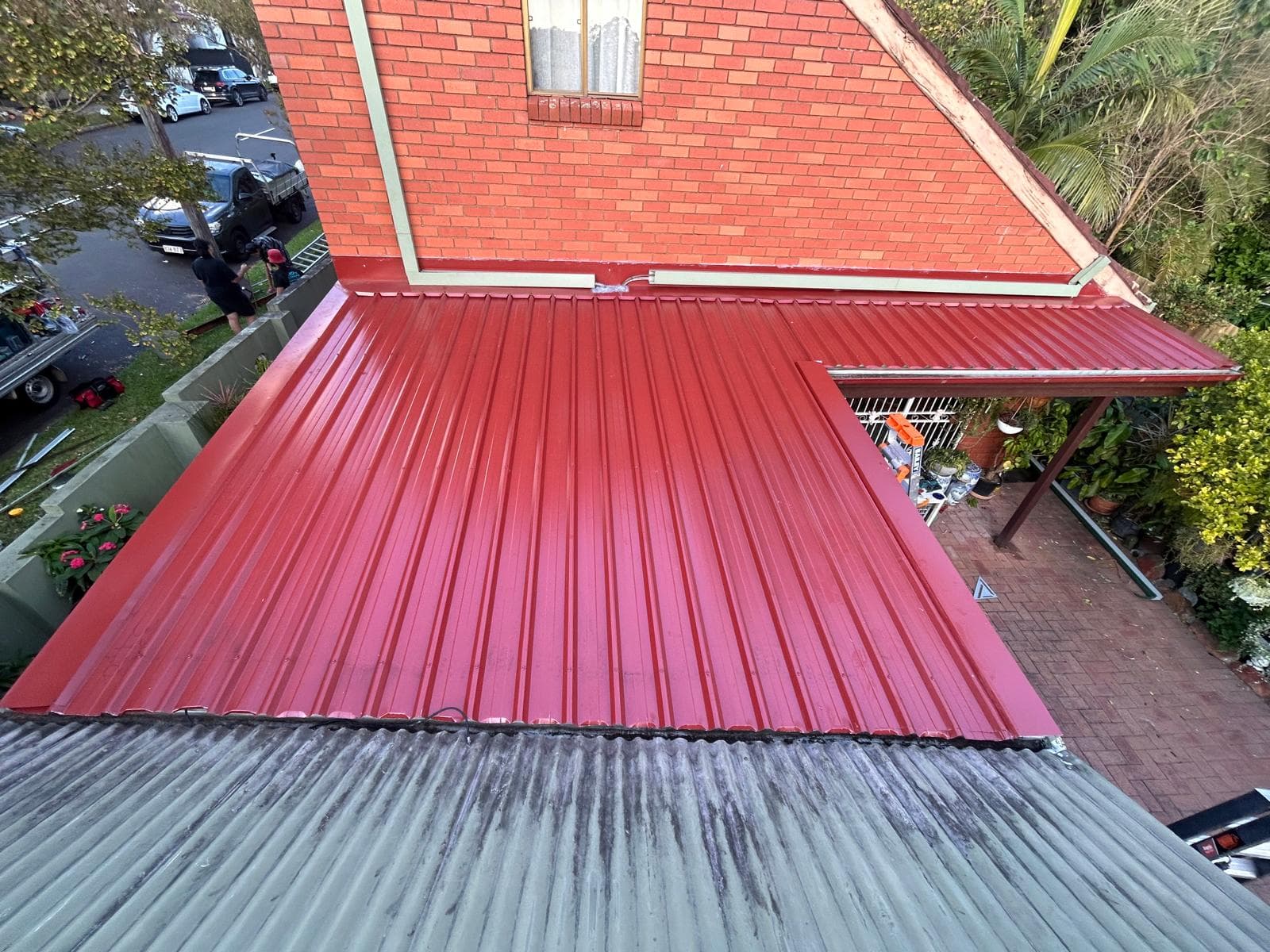 Overhead view of a red coated metal roof section on a residential extension