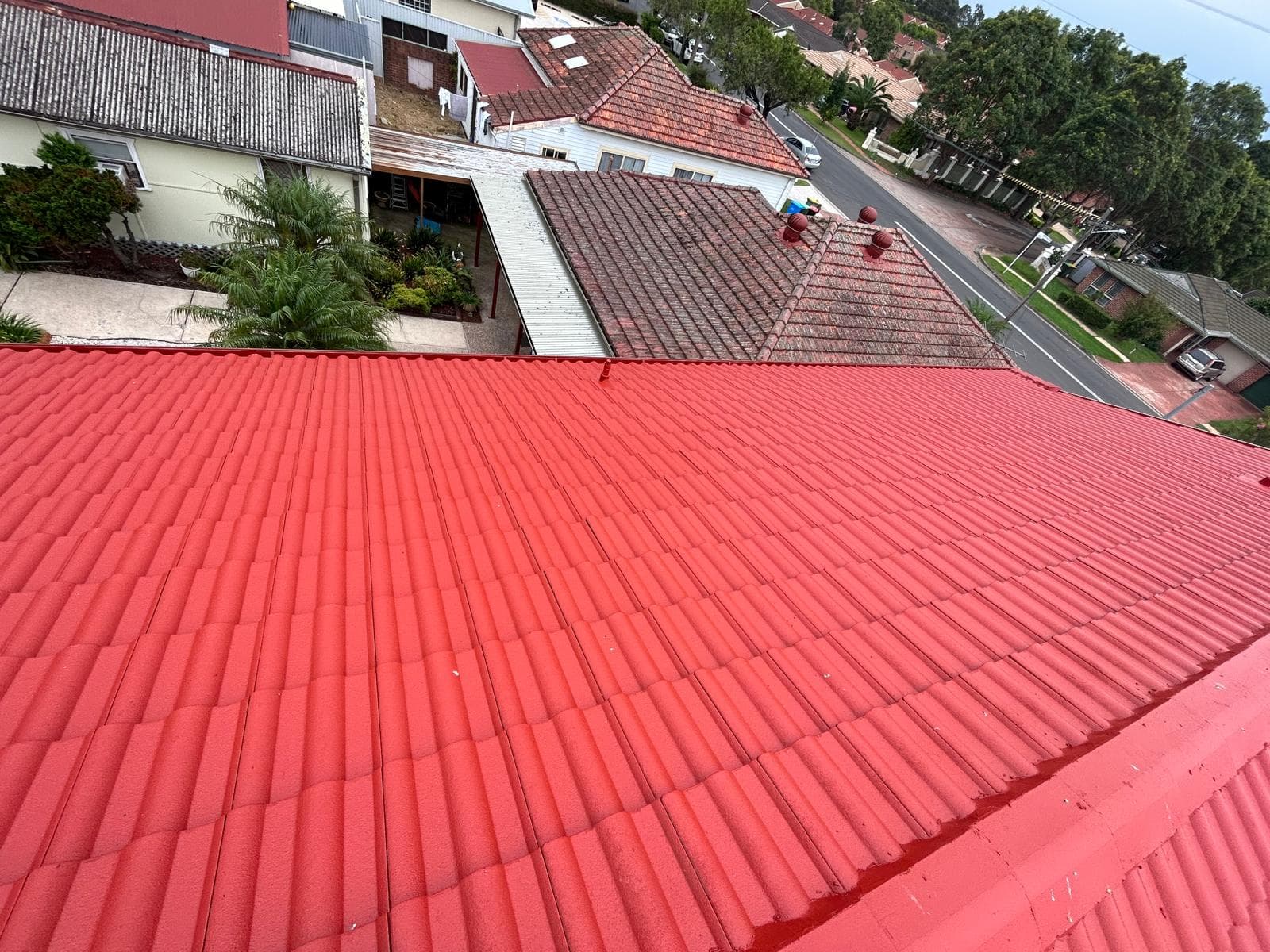 Wide view of red roof coating across a residential tile roof