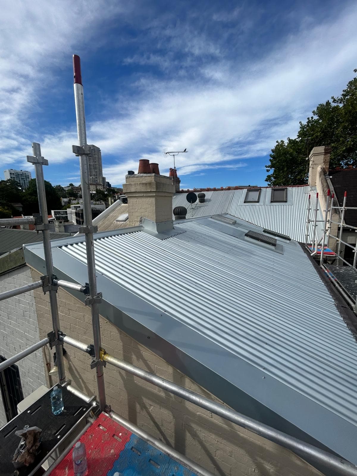 Light corrugated metal roof with skylights and chimney detailing