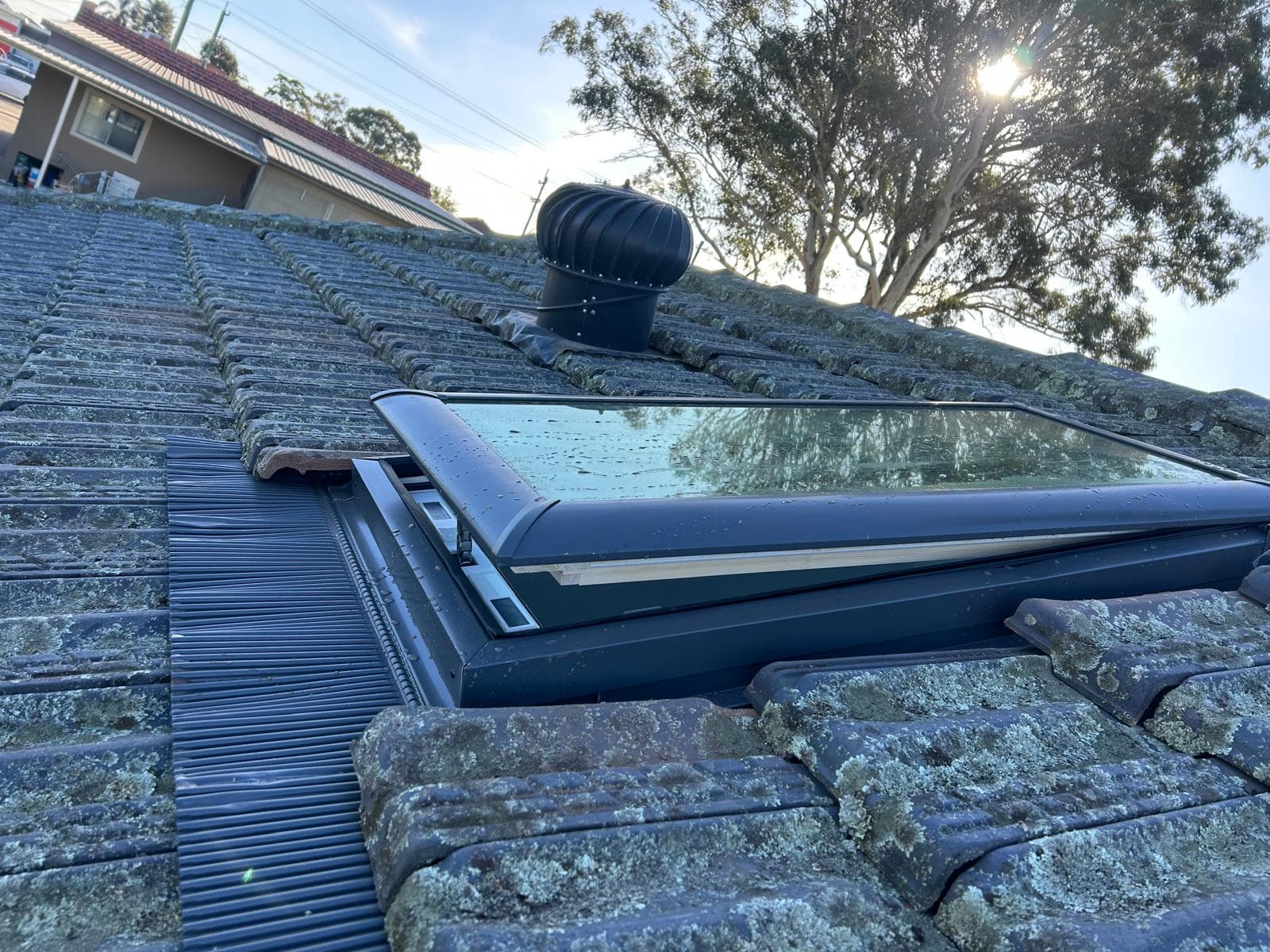 Tile roof ventilator and skylight on an older residential roof