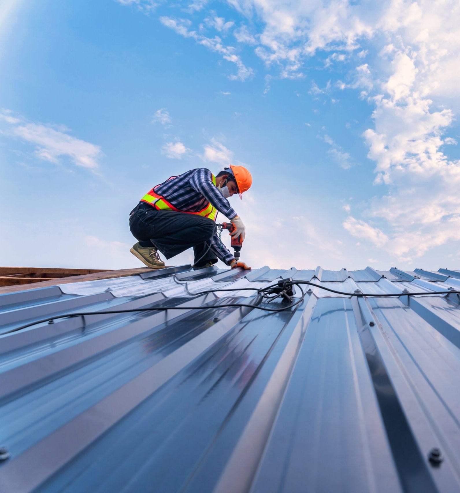 Worker beside roof-mounted equipment on a metal roof