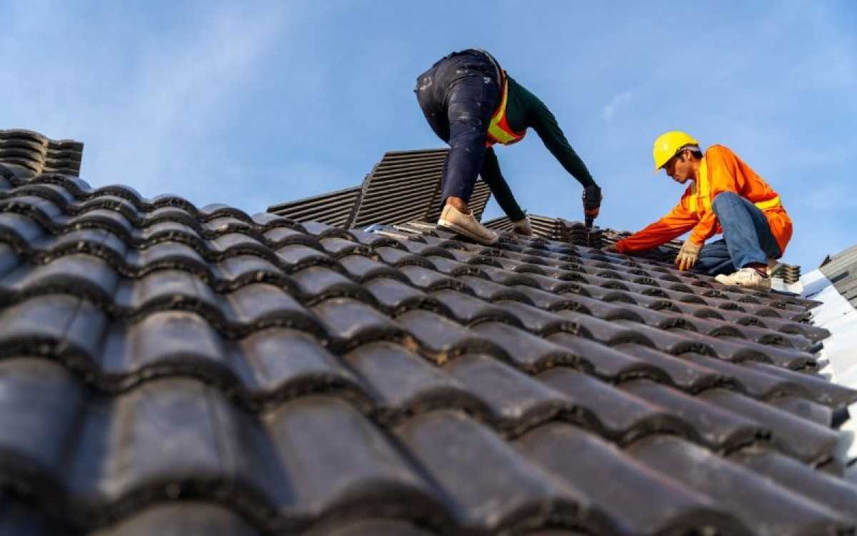Worker inspecting a pitched tiled roof