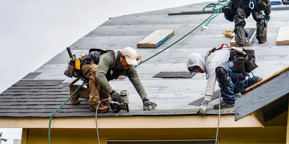 Workers near rooftop equipment on a metal roof