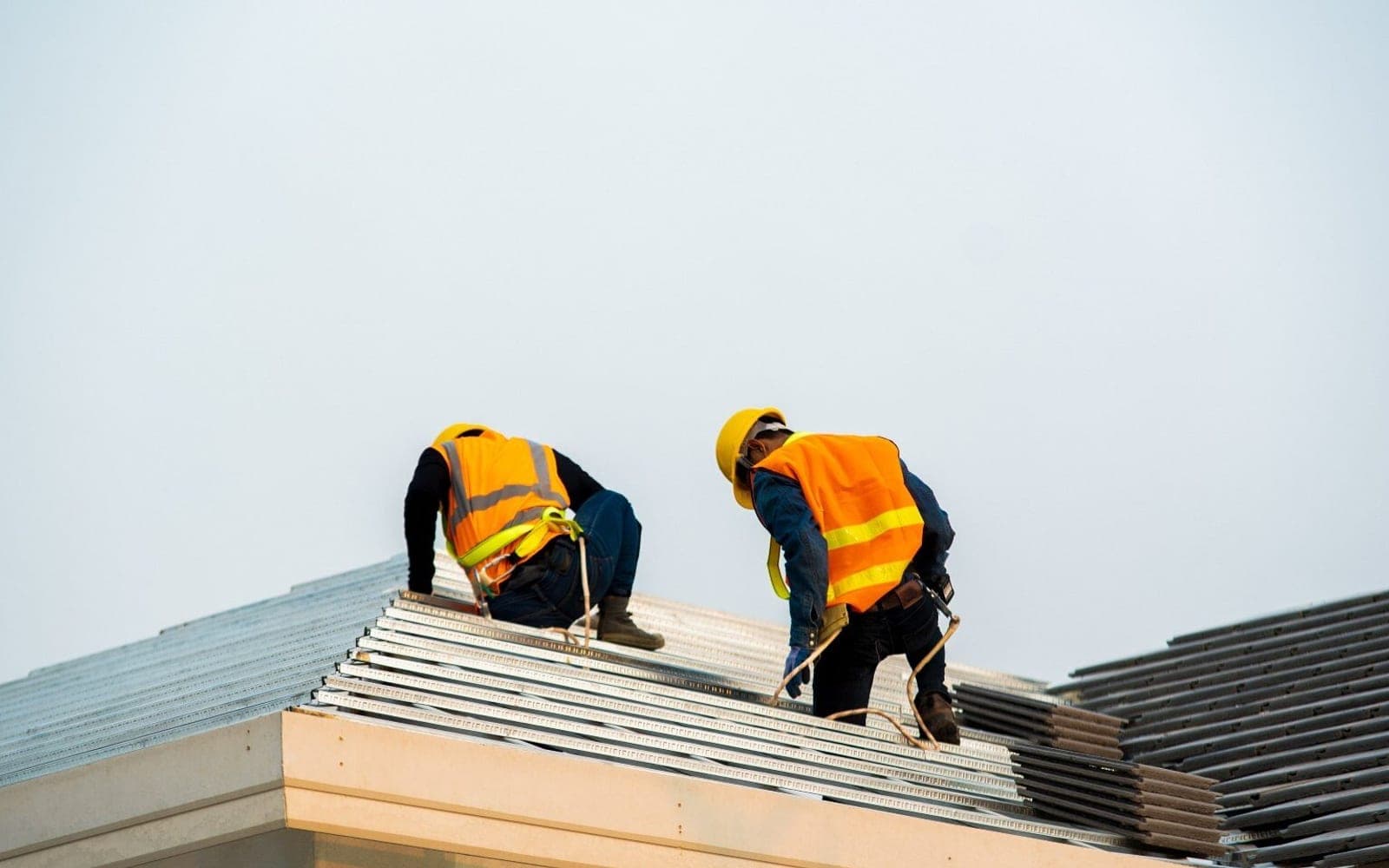 Workers beside corrugated metal roof sheeting
